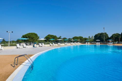 a large blue swimming pool with chairs and umbrellas at Camping Park Umag Mobile Homes in Umag