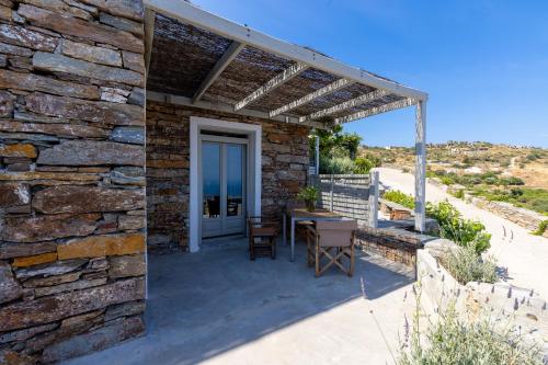 a stone walled patio with a table and chairs at Kea Village Suites & Villas in Ioulida