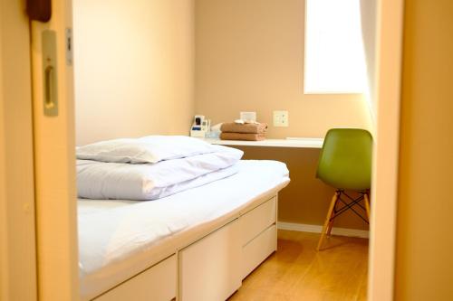 a bedroom with a bed and a green chair at コージーイン 東京桜新町 in Tokyo
