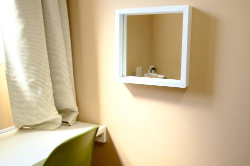 a mirror sitting on a wall next to a window at コージーイン 東京桜新町 in Tokyo