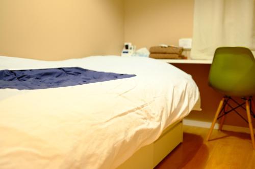 a bedroom with a bed and a green chair at コージーイン 東京桜新町 in Tokyo