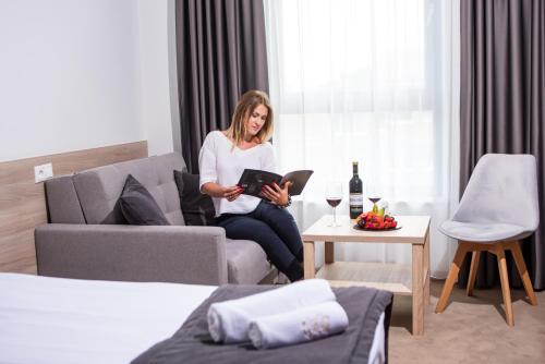 a woman sitting in a living room holding a book at Lubhotel in Lublin
