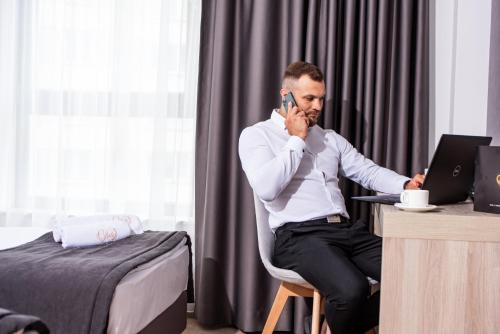 a man sitting at a desk talking on a cell phone at Lubhotel in Lublin