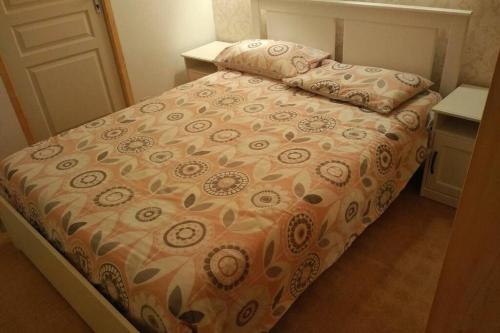 a bed in a small room with a bedspread and pillows at Le Petit Chalet in Bagnoles de l'Orne