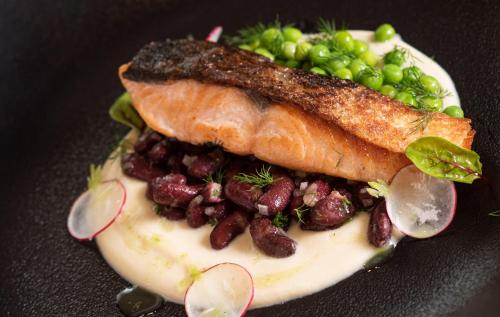 a plate of food with a piece of fish and peas at Lubhotel in Lublin