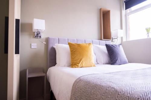 a bedroom with a bed with yellow and white pillows at Number 11 by the Warren Collection in Belfast