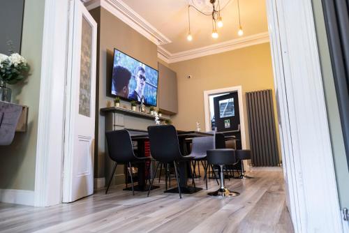 a dining room with a table and chairs and a flat screen tv at Number 11 by the Warren Collection in Belfast