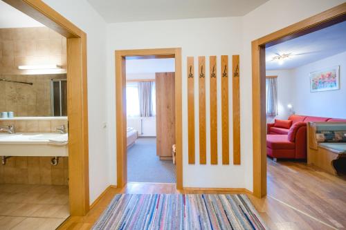 a bathroom with a sink and a living room with a couch at Apartmenthaus Kuchelberg in Altenmarkt im Pongau