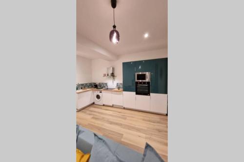 - une cuisine avec des placards blancs et un mur vert dans l'établissement La perle du Panier, à Marseille