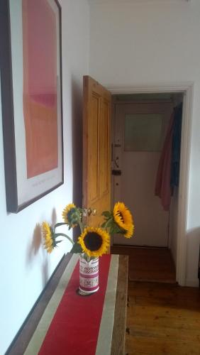 un jarrón lleno de girasoles sentado en una mesa en Homey, warm & welcoming room., en Londres