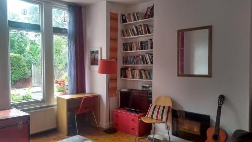 uma sala de estar com televisão e uma prateleira com livros em Homey, warm & welcoming room. em Londres