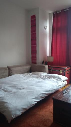 a large bed in a bedroom with a red curtain at Homey, warm & welcoming room. in London