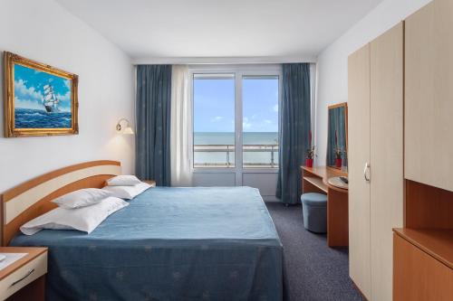 a hotel room with a bed with a view of the ocean at Hotel Sirena Saturn All Inclusive in Saturn