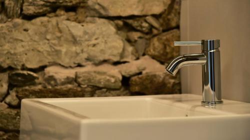 a bathroom sink with a faucet in front of a stone wall at Il Ronchetto in Cunardo