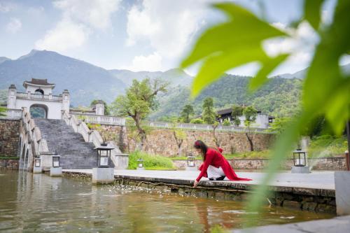 a woman standing on a dock near a body of water at Làng Nương Yên Tử (Yên Tử Village) in Uông Bí