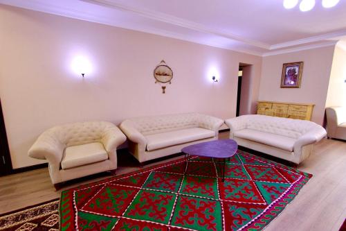 a living room with two couches and a rug at Muras Hotel Karakol in Karakol