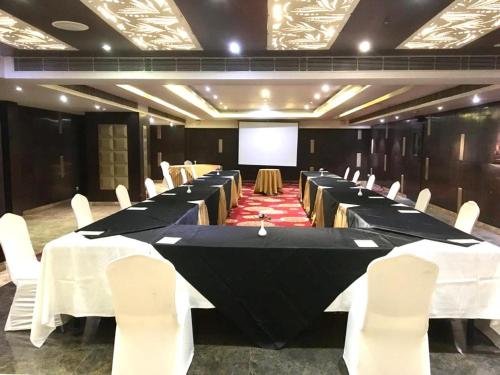 a conference room with tables and chairs and a screen at Souvenir Jaipur in Jaipur