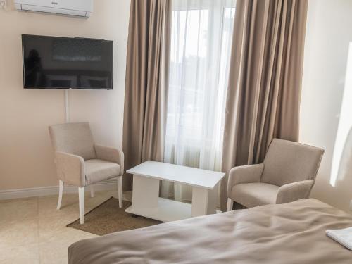 a hotel room with a bed and two chairs and a television at A klub apartmani in Mrčajevci