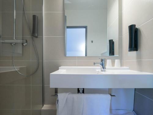 uma casa de banho com um lavatório e um chuveiro com um espelho. em Noemys Viviers-du-lac em Viviers-du-Lac