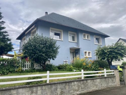 a blue house with a white fence in front of it at La chambre Plume in Truchtersheim