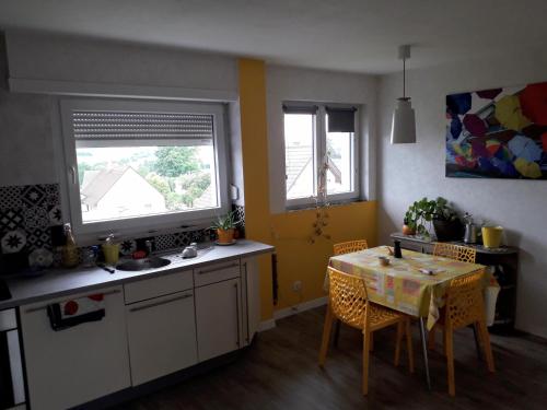 a kitchen with a table and a table and two windows at La chambre Plume in Truchtersheim