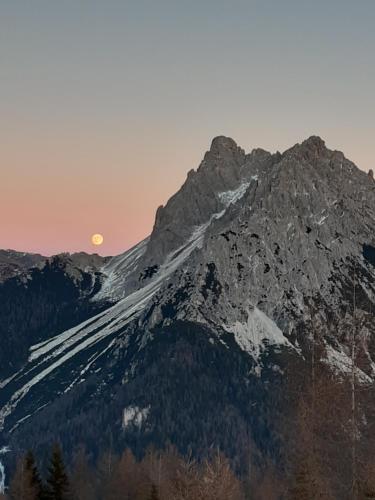 a mountain with the sun setting behind it at Al Sole B&B Valcomelico in Santo Stefano di Cadore