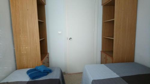 マタラスカニャスにあるApartamento Virgen de la Sierraのベッドルーム(ベッド2台、木製キャビネット付)