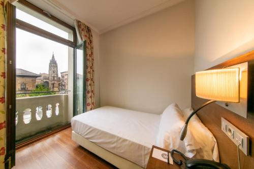 1 dormitorio con cama y ventana grande en Soho Boutique Oviedo en Oviedo
