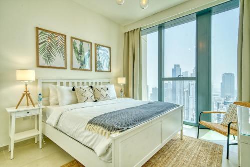 um quarto com uma cama branca e janelas grandes em Boho-Chic Cosy 1BR, minutes to Burj Khalifa em Dubai