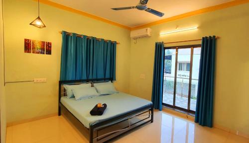 a bedroom with a bed with blue curtains and a window at Swarg 5Bhk Villa Alibaug in Alibaug