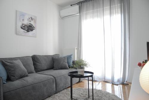 a living room with a gray couch and a table at Apartment DobraYa Grey in Novi Sad