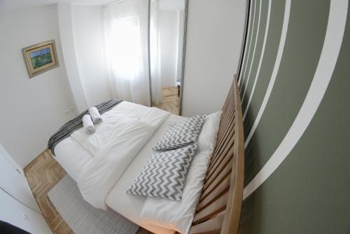 a small bedroom with a bed with white sheets and pillows at Apartment DobraYa Grey in Novi Sad