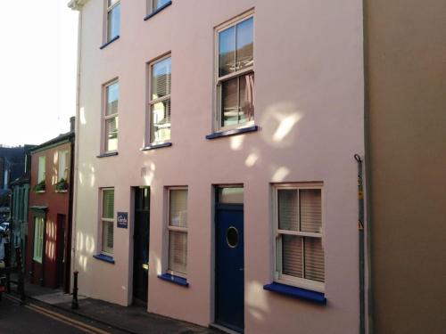 a white building with a blue door on a street at Garda House in Kinsale