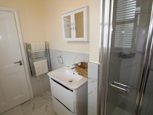 a white bathroom with a sink and a shower at Garda House in Kinsale