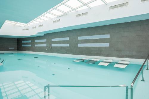 a swimming pool with blue water in a building at Hotel Balneario Playa de Comarruga in Comarruga