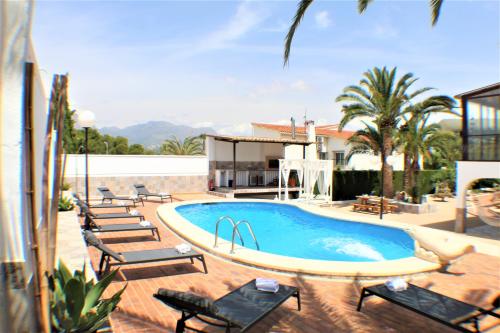 a swimming pool with chairs and a house at VILLA COSTA LEVANTE BENIDORM in Benidorm
