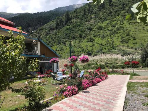 a garden with flowers in front of a house at Parhena Cottages Bella Naran in Nārān