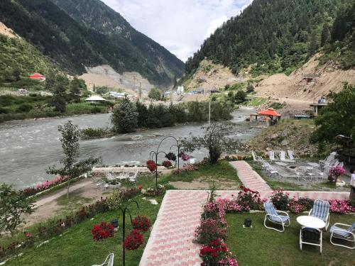 a view of a river with chairs and flowers at Parhena Cottages Bella Naran in Nārān
