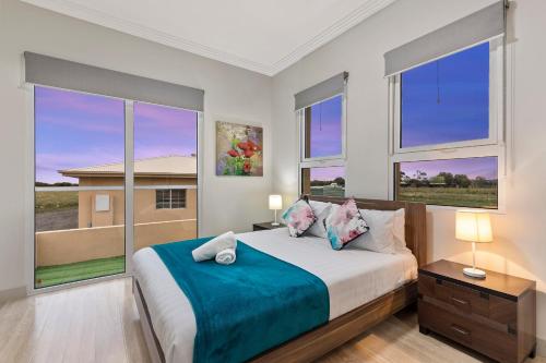 a bedroom with a large bed with two windows at 5 Bdrms Loemans Lodge - Close to Calder Park, Melb Airport in Bulla