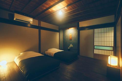 a bedroom with two beds and a window and lights at Kominkayado LOOF Sannoie in Koike