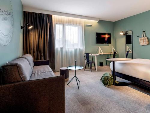 ein Schlafzimmer mit einem Bett, einem Sofa und einem Tisch in der Unterkunft ibis Styles Limoges Centre in Limoges