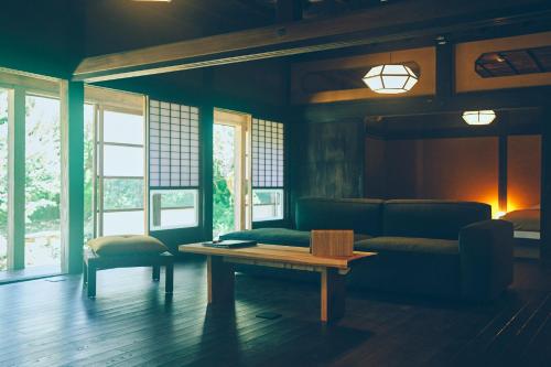 a living room with a couch and a table at Kominkayado LOOF Sannoie in Koike