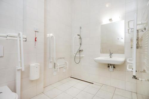 a white bathroom with a sink and a shower at Poznań West Hotel - Airport in Poznań