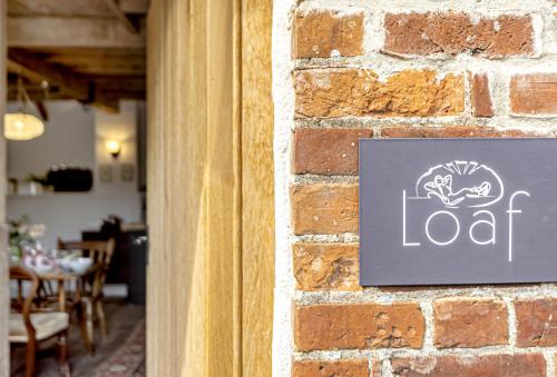 a sign on the side of a brick wall at Loaf in Bridport