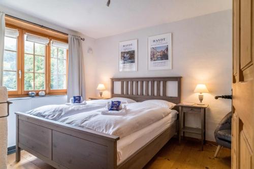 a bedroom with a large bed and two windows at Apartment Rybibach Retreat in Lauterbrunnen