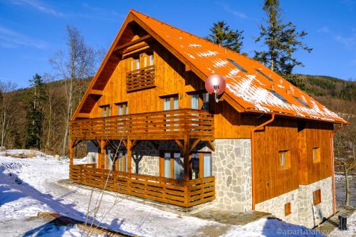 a log cabin with an orange roof in the snow at Apartmány Valča in Valča