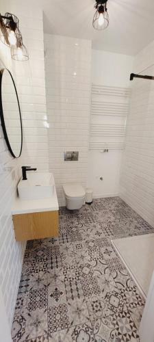 a white bathroom with a sink and a toilet at Central Apartments Ogrody 3 & Parking in Gdańsk