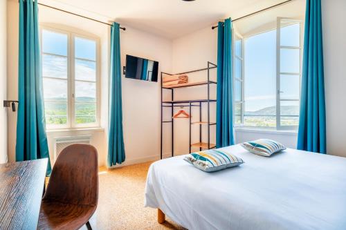 a bedroom with blue curtains and a bed and a window at Le Nesk Ventoux - Hotel in Sault-de-Vaucluse