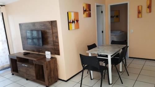 a dining room with a table and chairs and a television at Porto de Iracema Residence in Fortaleza