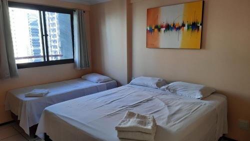 two beds in a room with a window and a picture at Porto de Iracema Residence in Fortaleza